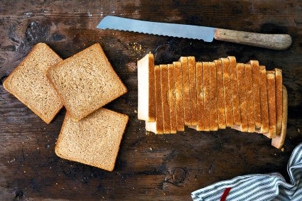 Whole wheat bread baked in a pain de mie pan, sliced on a board.